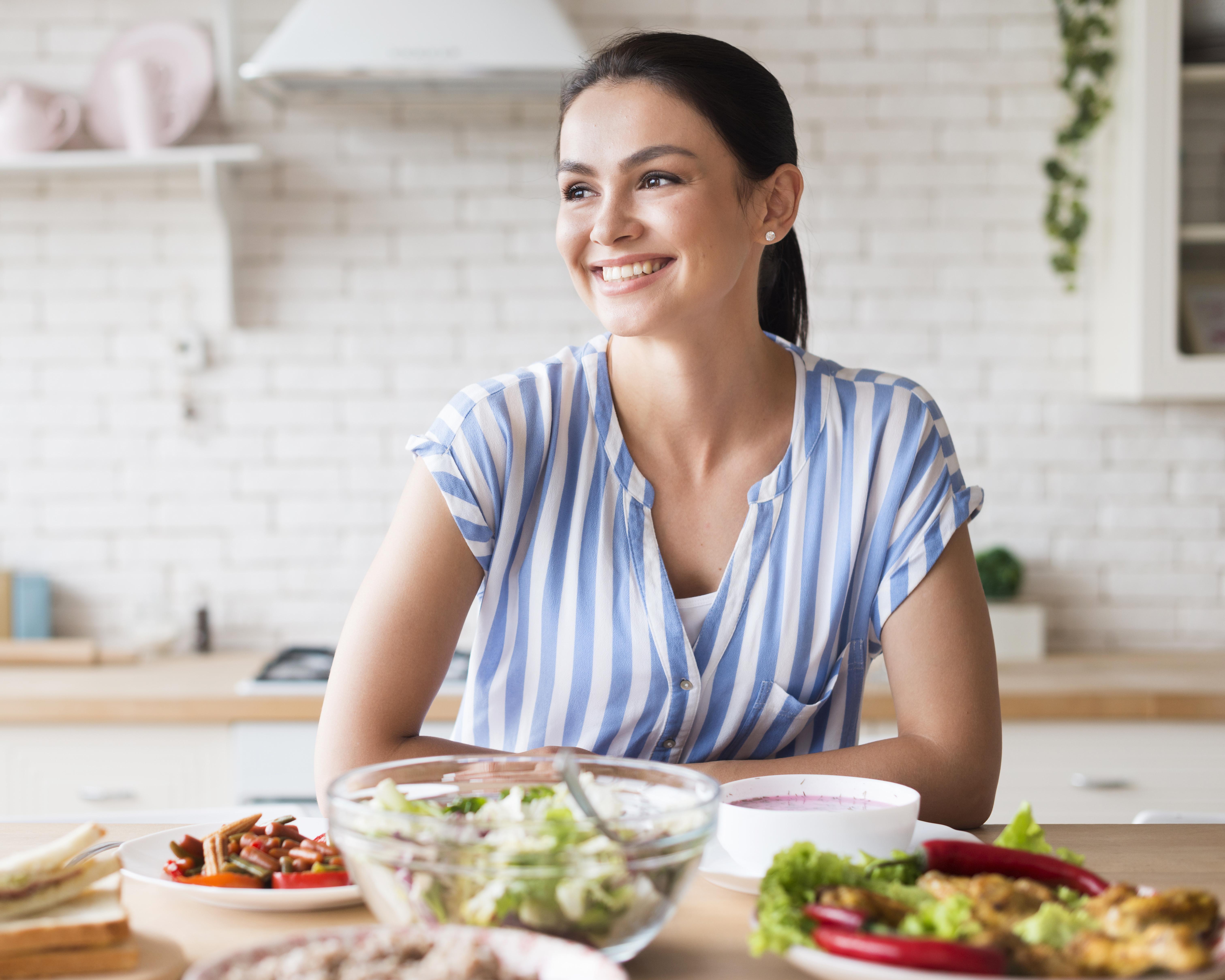 Mujer sonriendo sentada en frente de platos de comida