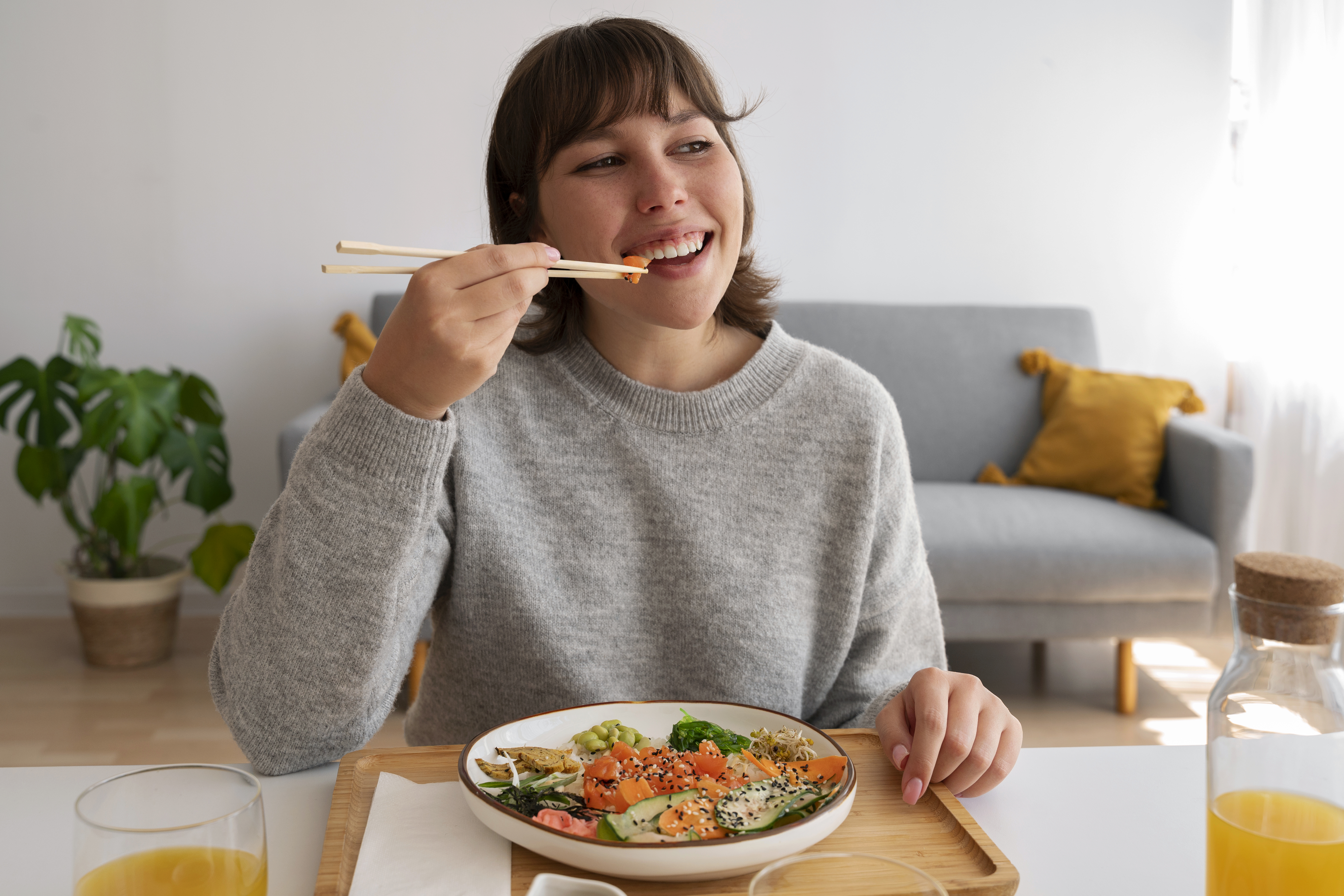 Mujer de sueter gris comiendo arroz